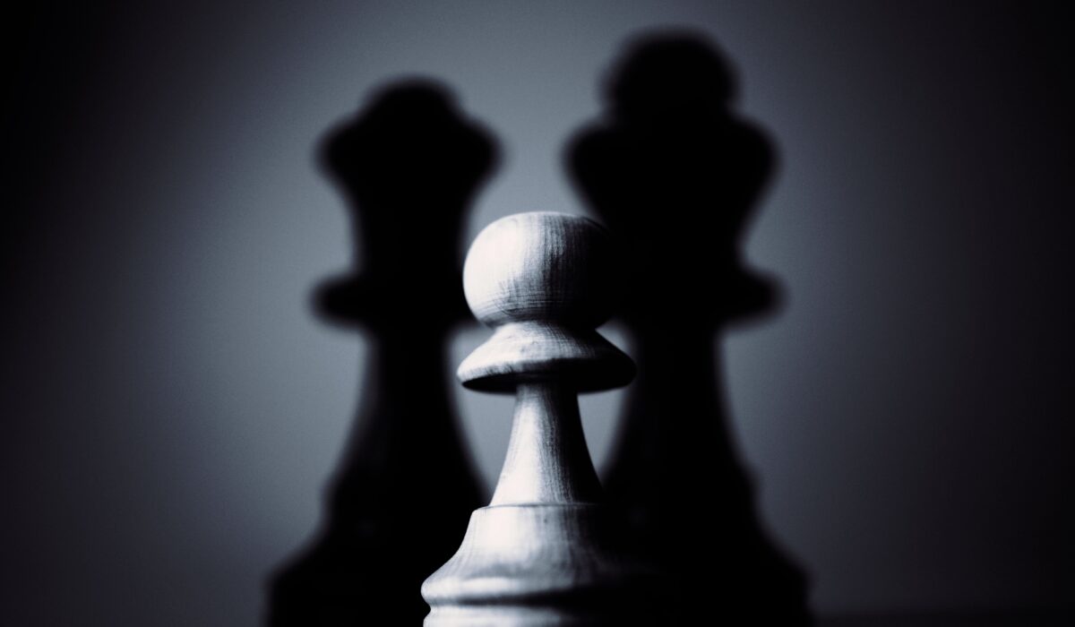 Moody black and white photograph of a chess pawn highlighting strategy and shadow play.