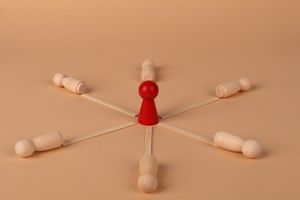 Red leader figure connected to wooden figures, emphasizing leadership and teamwork.